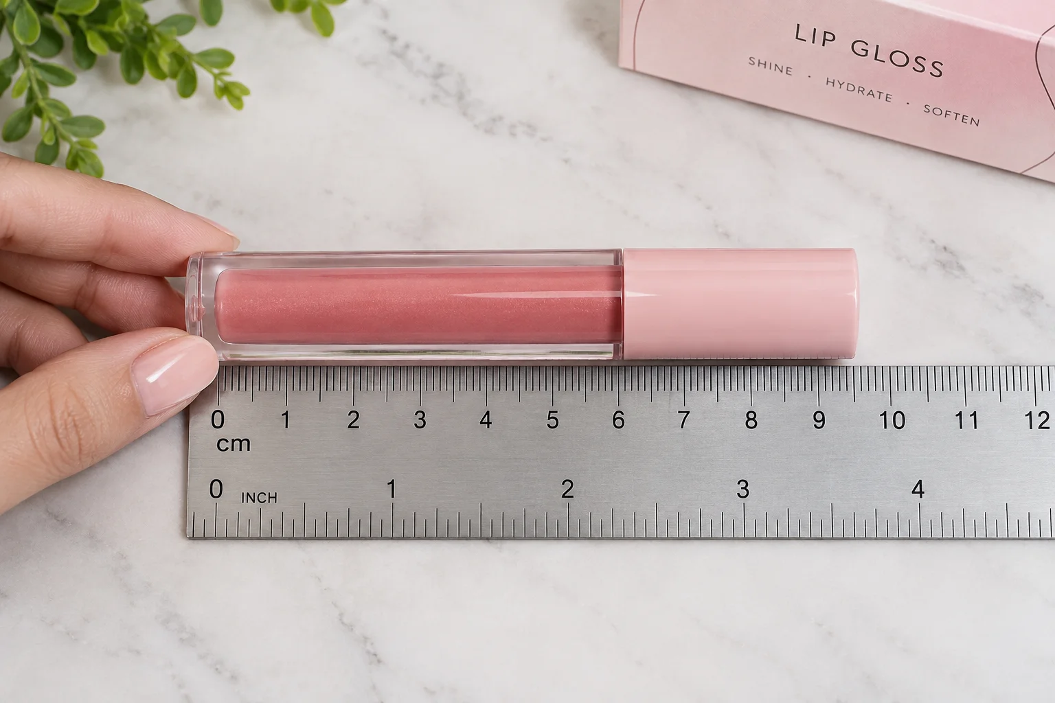 measuring a closed doe foot lip gloss tube against a rule